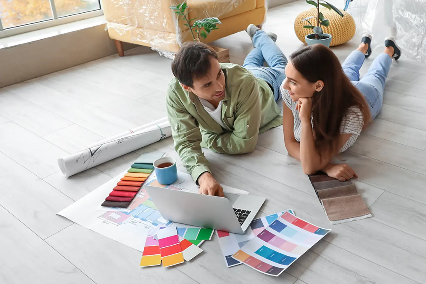 Pareja joven renovando piso, eligiendo en línea tarima y papel pintado.