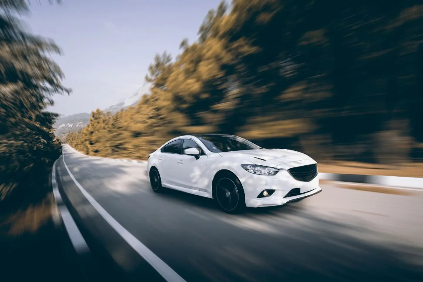 Coche blanco circulando por una carretera rural