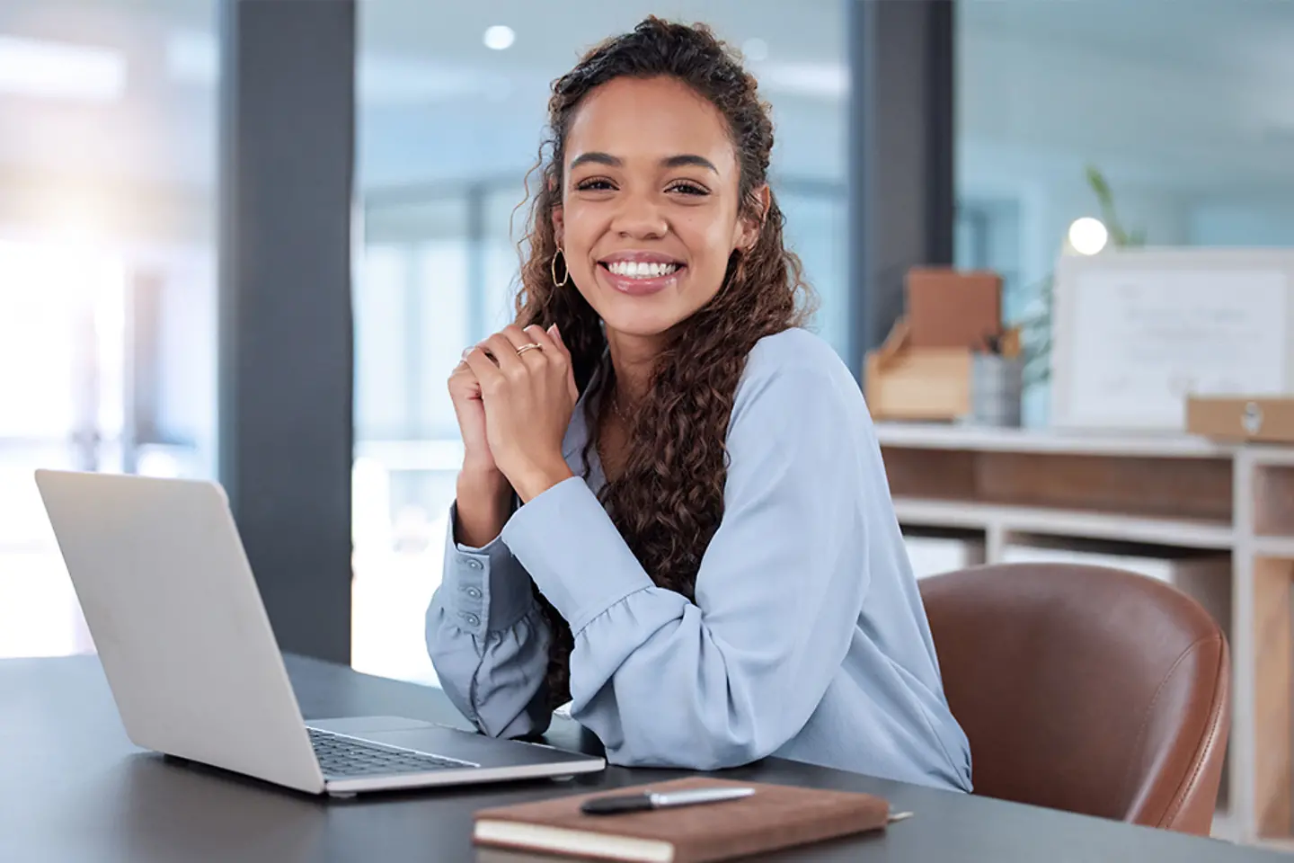 Female office worker smiling happily in front of laptop